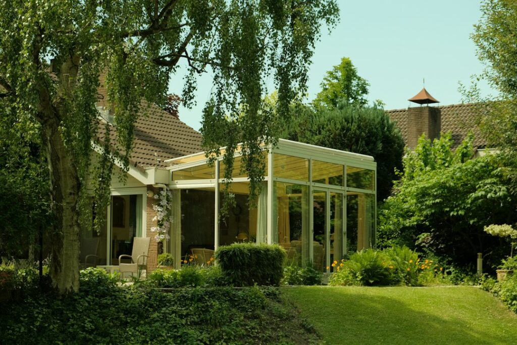 Véranda vitrée attenante à une maison dans un jardin